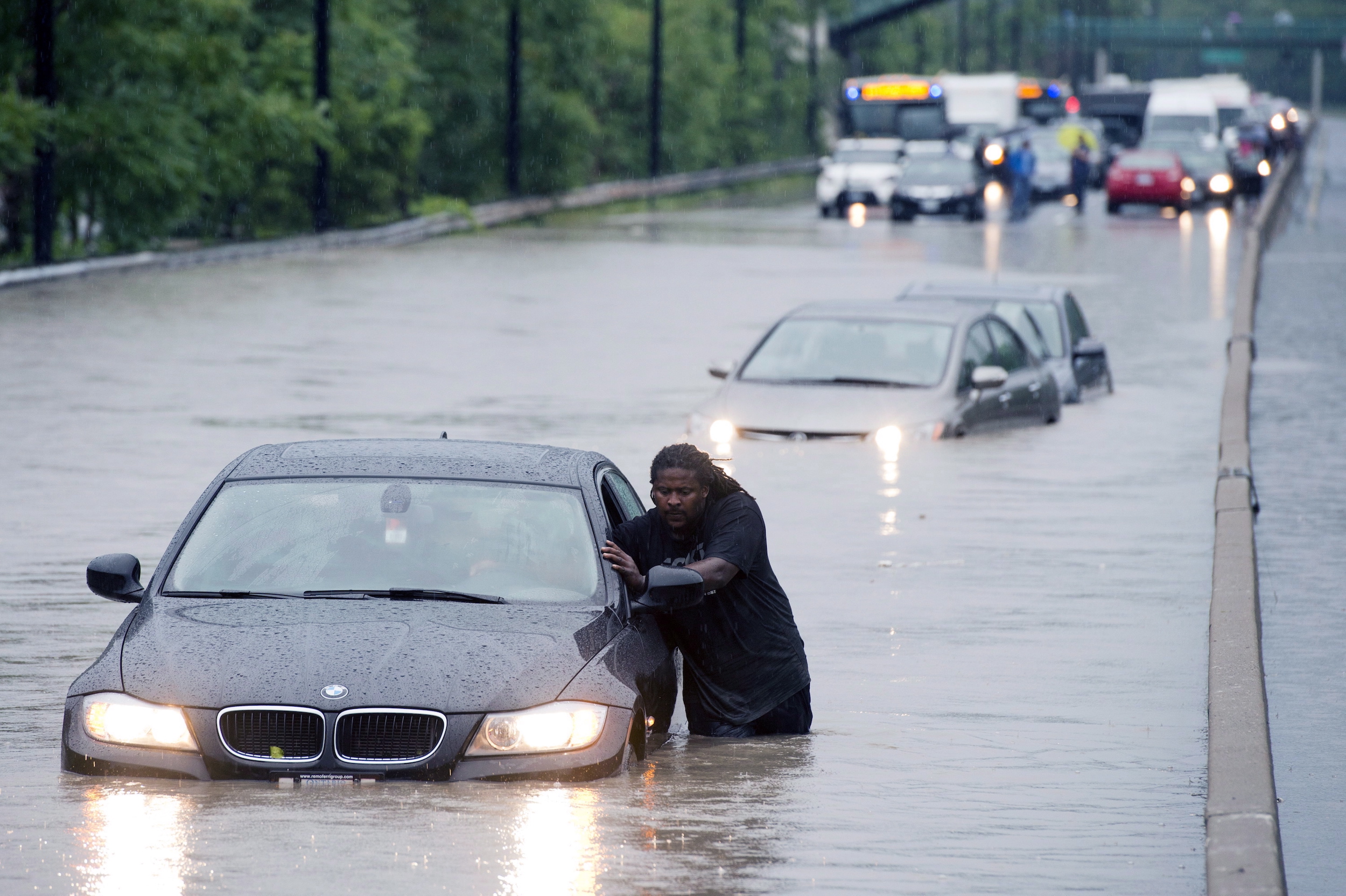 A tow truck driver floats a car out of the Don Valley Parkway in Toronto on Monday, July 8 2013.