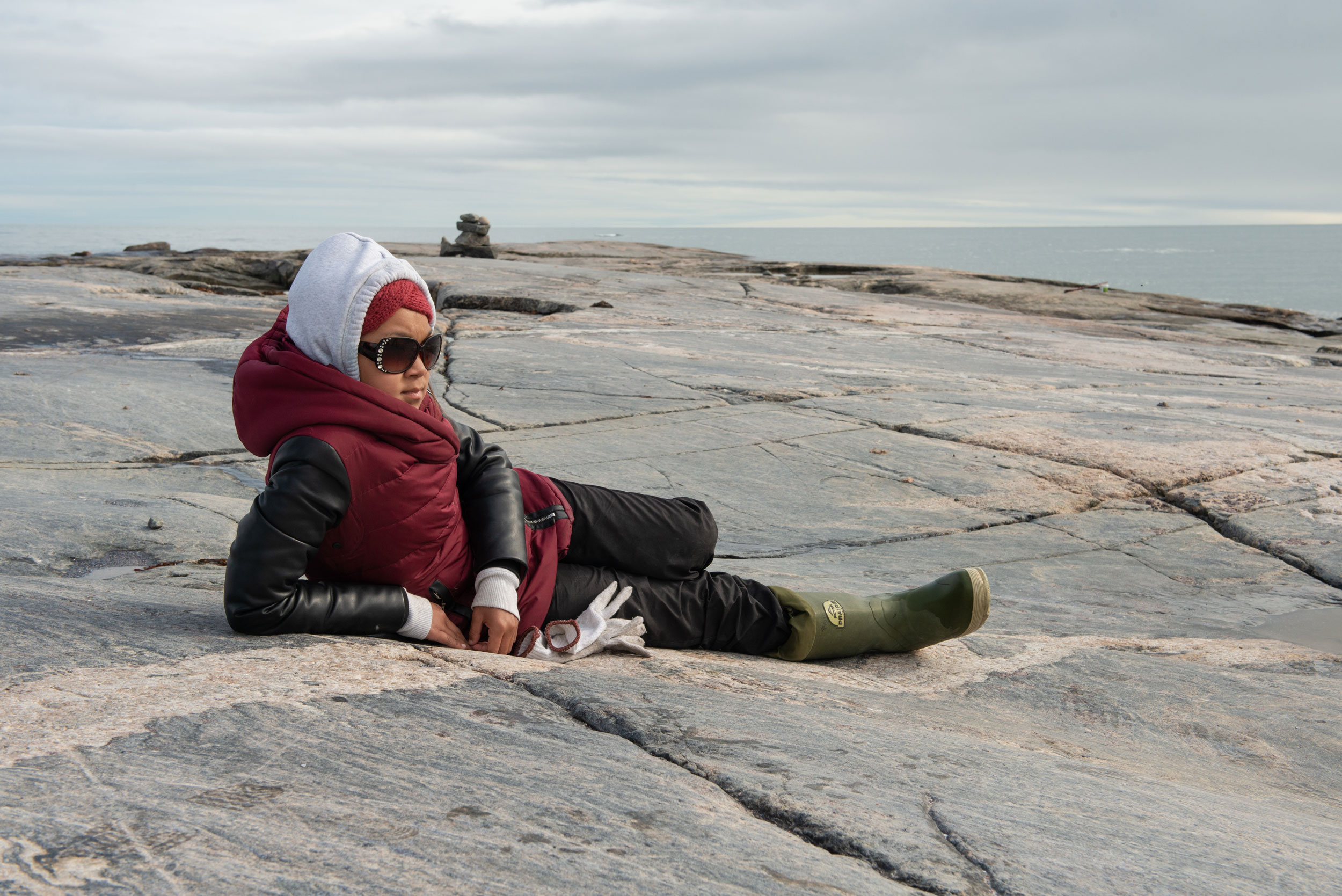 Rolanda Uquuyuq Tiktaq, a participant in the Aqqiumavvik Society’s Ujjiqsuiniq Young Hunters program relaxes on a rocky islet in Hudson Bay, while her group waits for belugas.