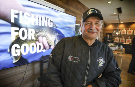 Cedar Lake fishery president Floyd George stands in front of a screen reading "fishing for good" during a sustainable fishing announcement in Winnipeg