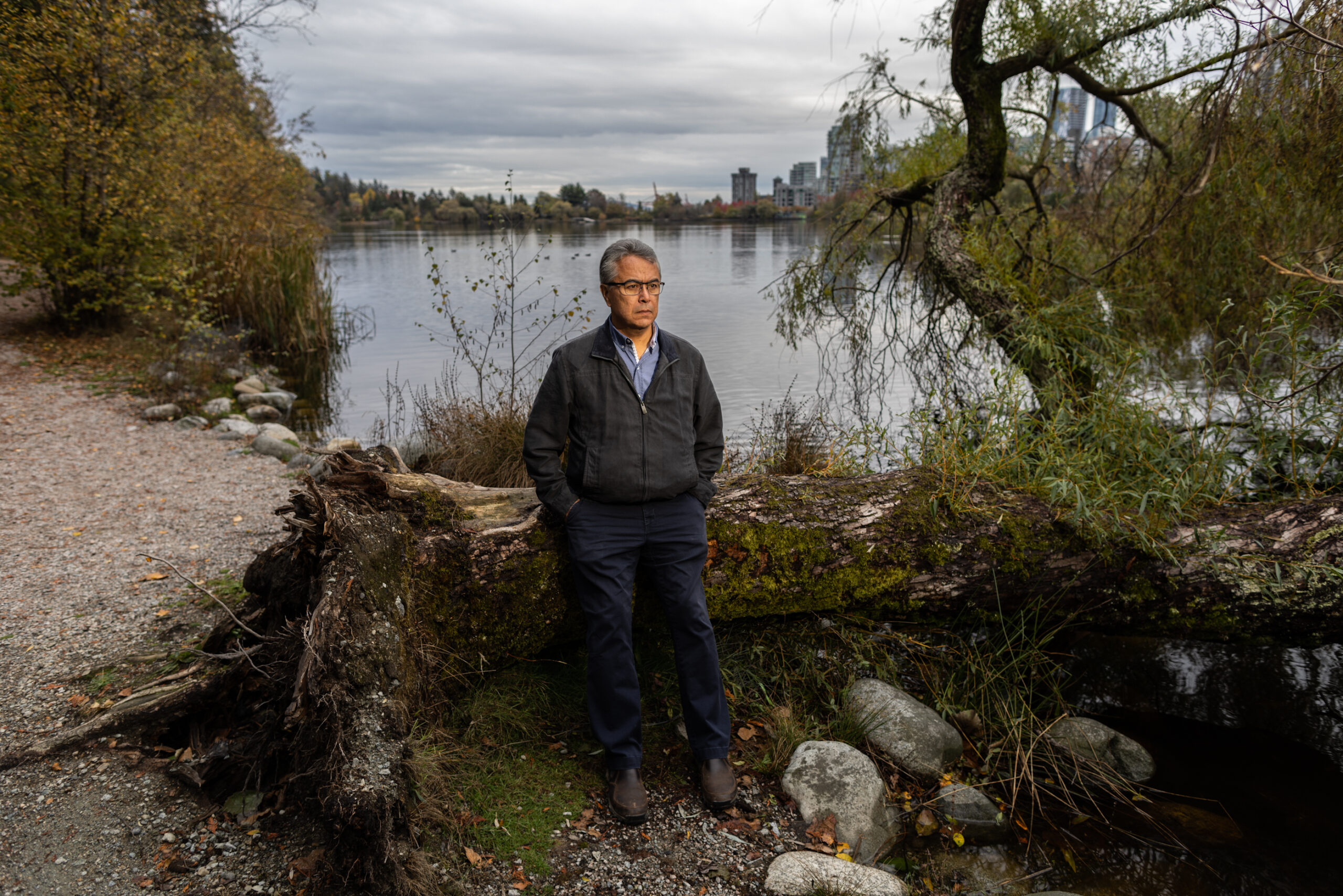 A man poses in front of a bay with a cityscape in the background