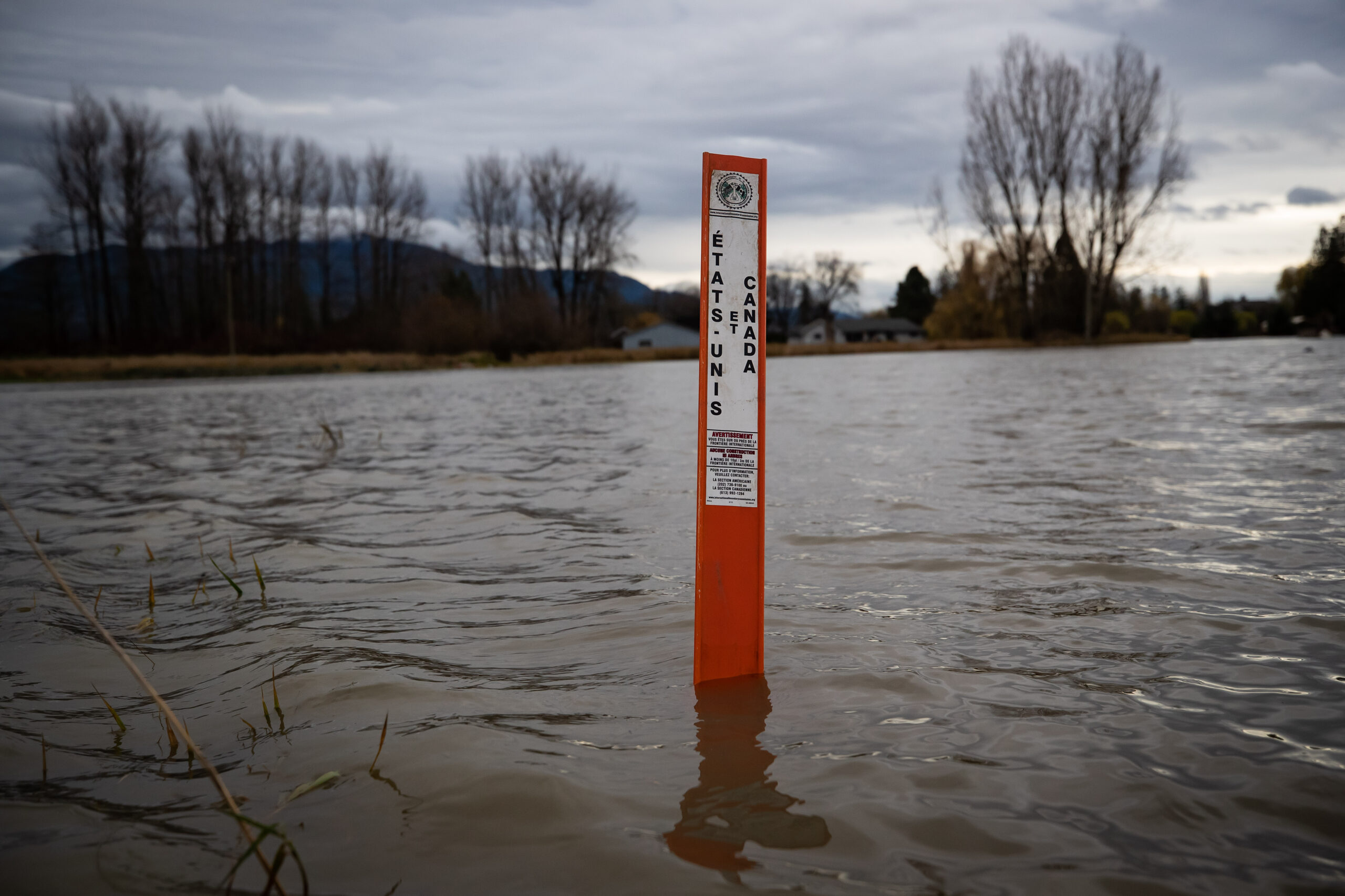 A Canada-U.S. border marker is seen surrounded by floodwaters flowing into Abbotsford, B.C., from the U.S. in 2021.