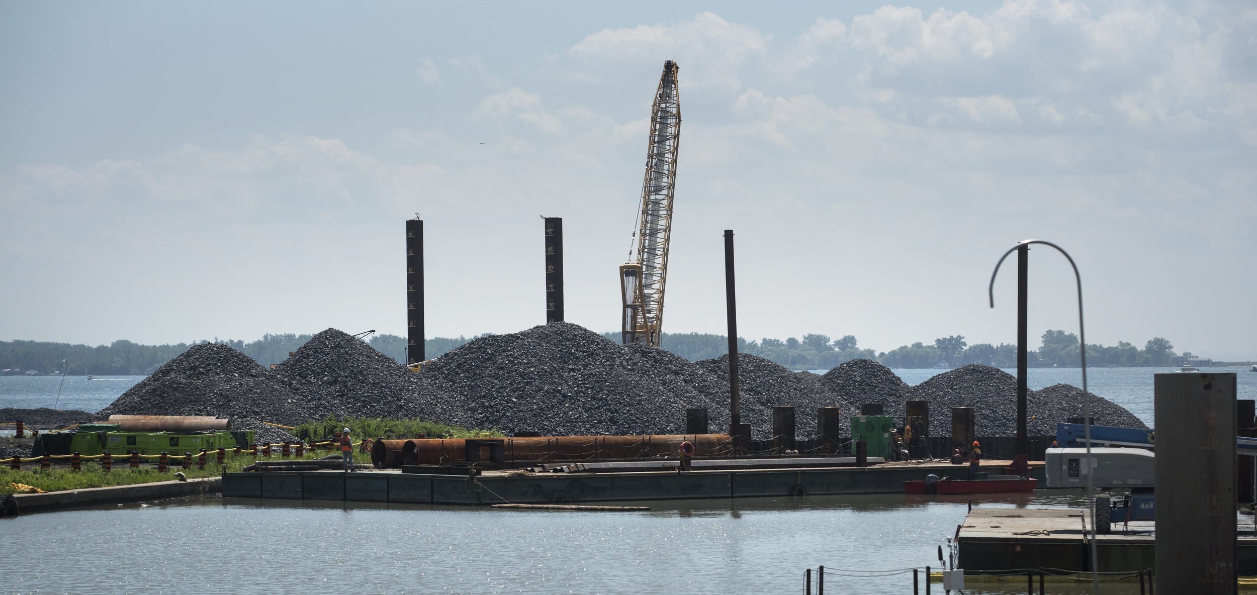 Piles of rock and a crane at the edge of a harbour