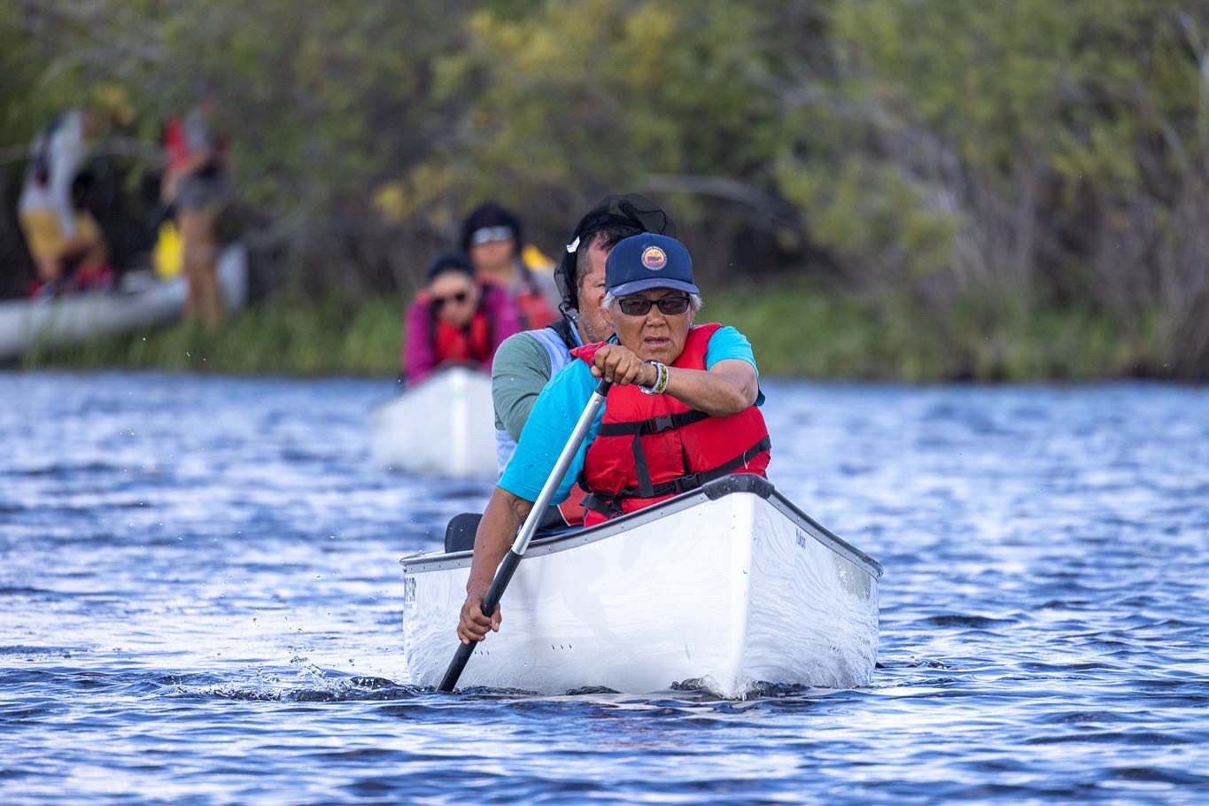 Members of Seal River's land guardian program paddle canoes through a lake