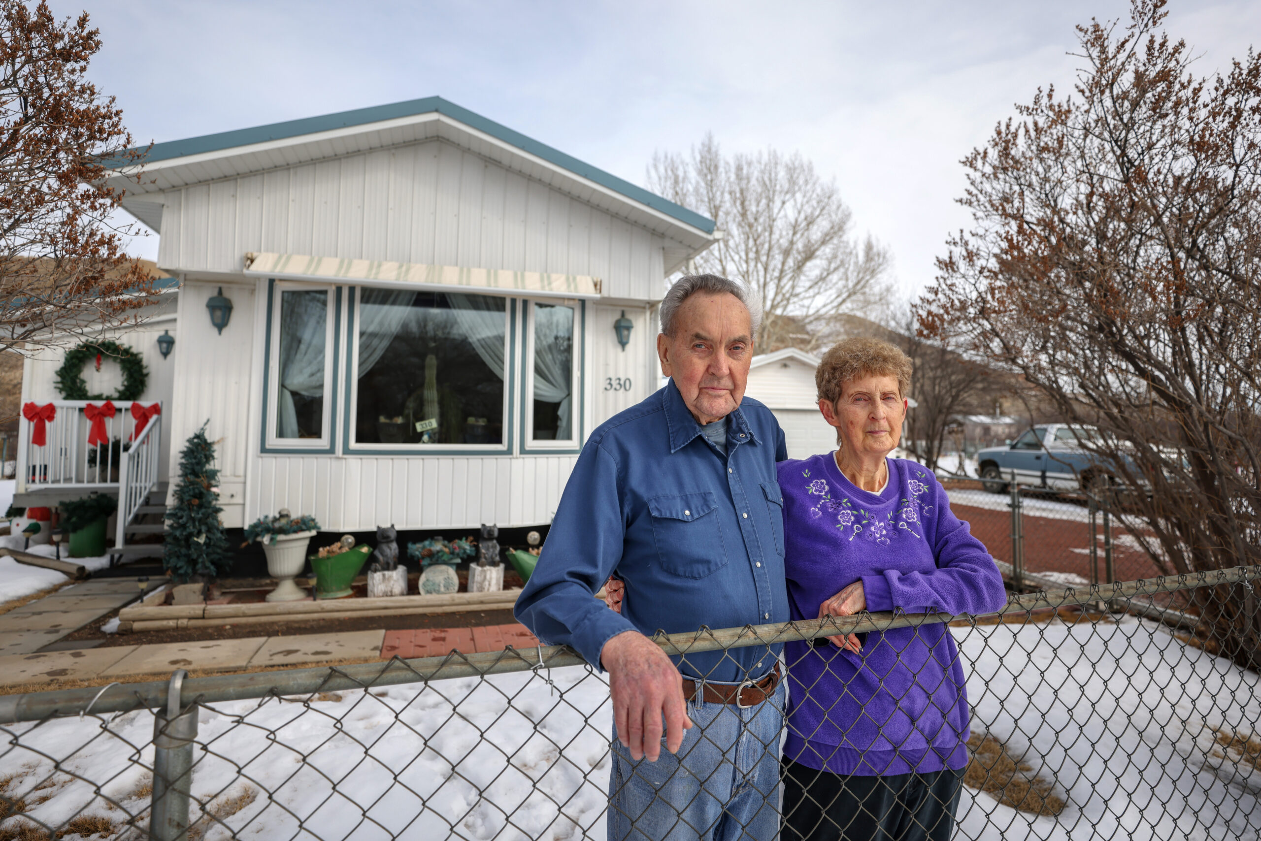 An older couple pose in front of a trailer in Lehigh, Alta