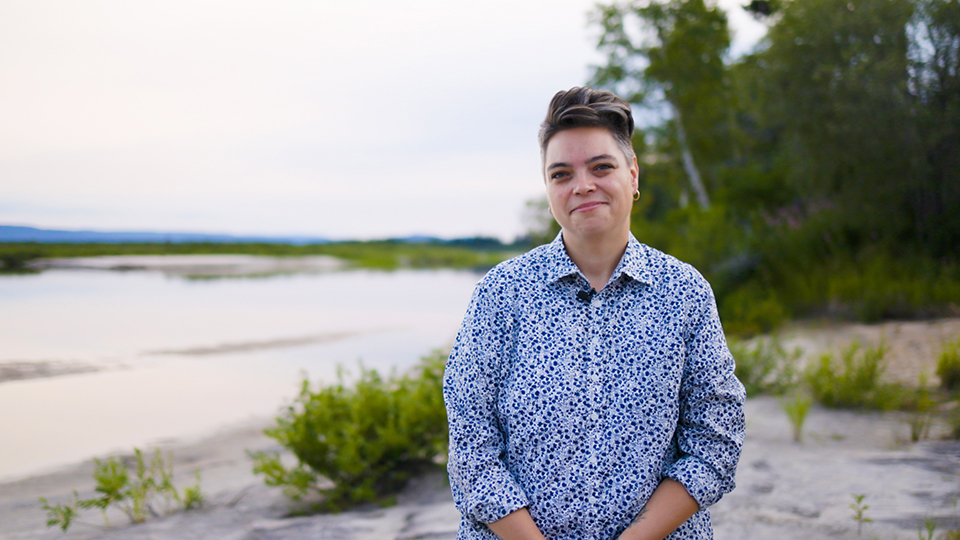 Director of the Indigenous Leadership Initiative Valerie Courtois wears a patterned blue shirt in front of a beach