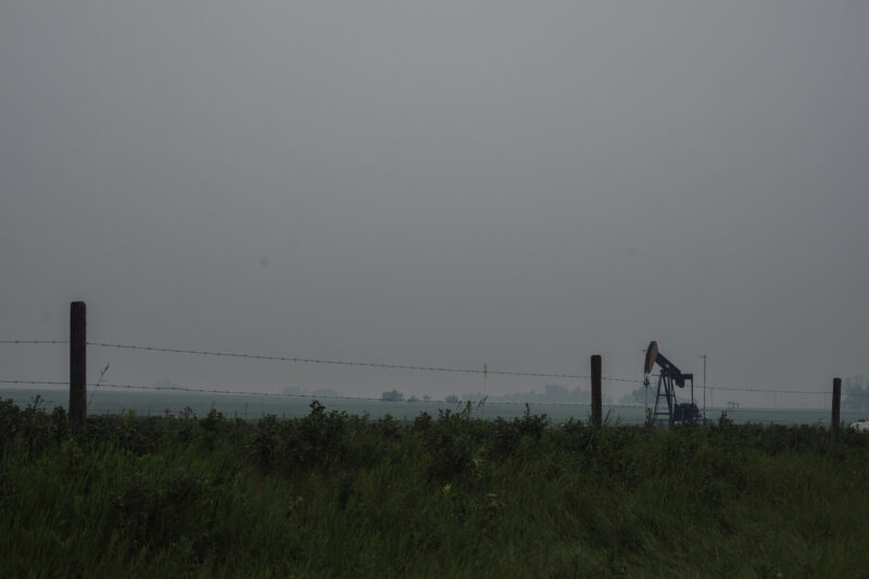 Oil well on smoky Alberta landscape