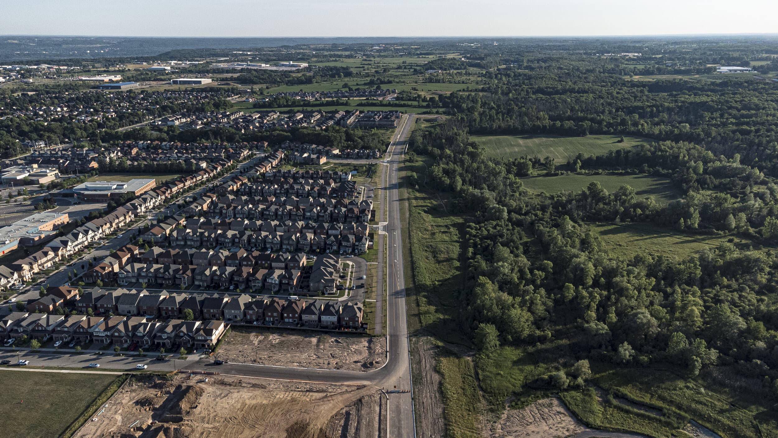 An aerial shot of suburban housing development with an imaginary but definite line separating it from a bushy forest