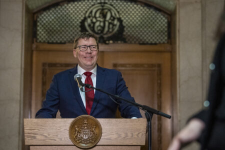 Saskatchewan Premier Scott Moe stands in front of a lectern, speaking to media