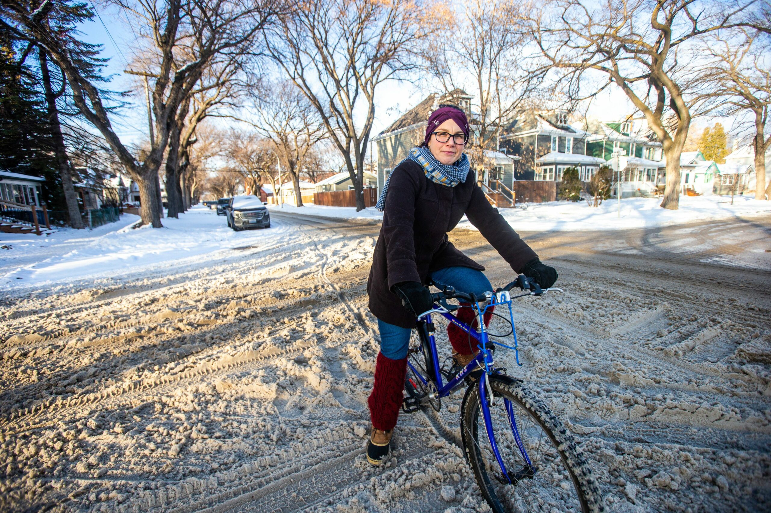 Mel Marginet with Manitoba's Green Action Centre sits on a blue bicycle in a snow-covered intersection in Winnipeg