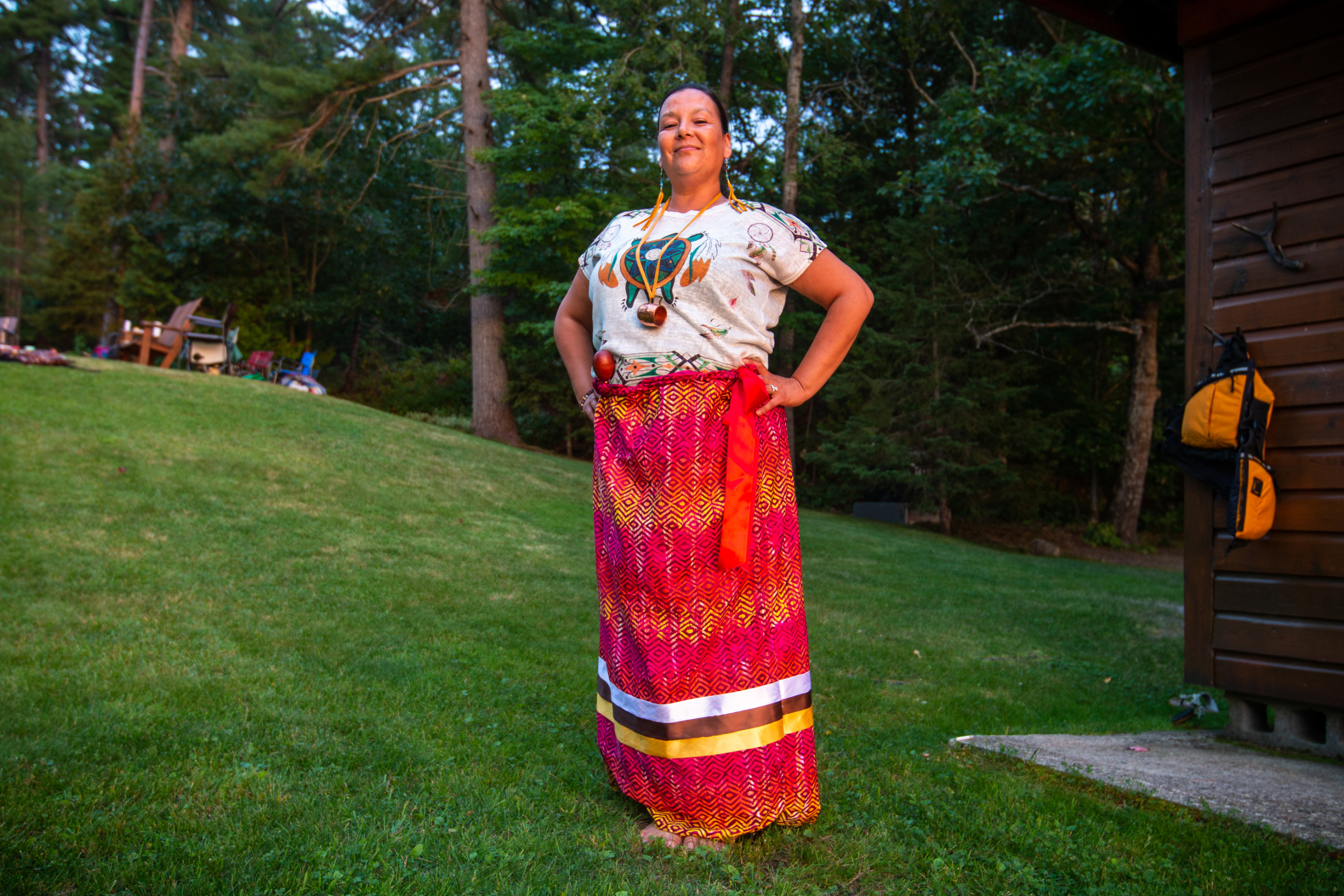 Lesley Chiblow poses in golden light, wearing a ribbon skirt and shirt with a turtle on it