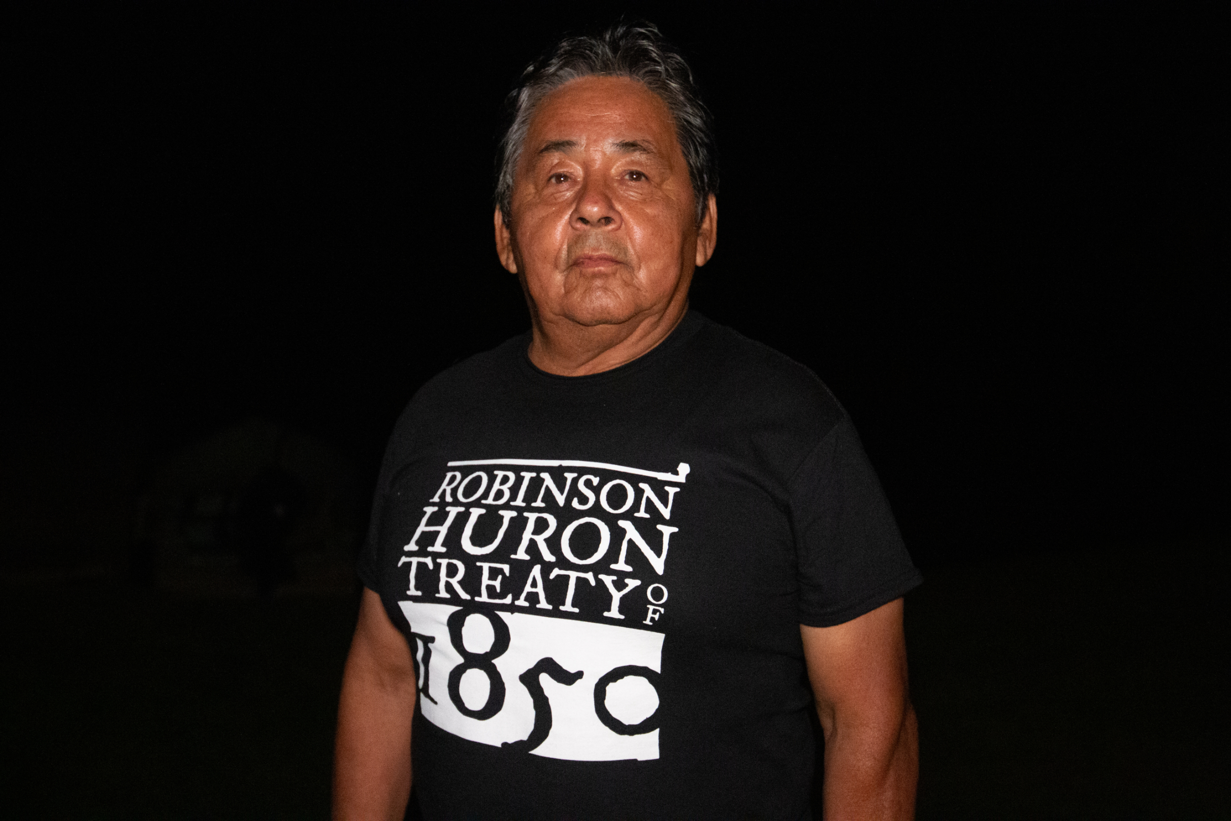 Ken Meawasige wearing a shirt that says "Robinson Huron Treaty of 1850"