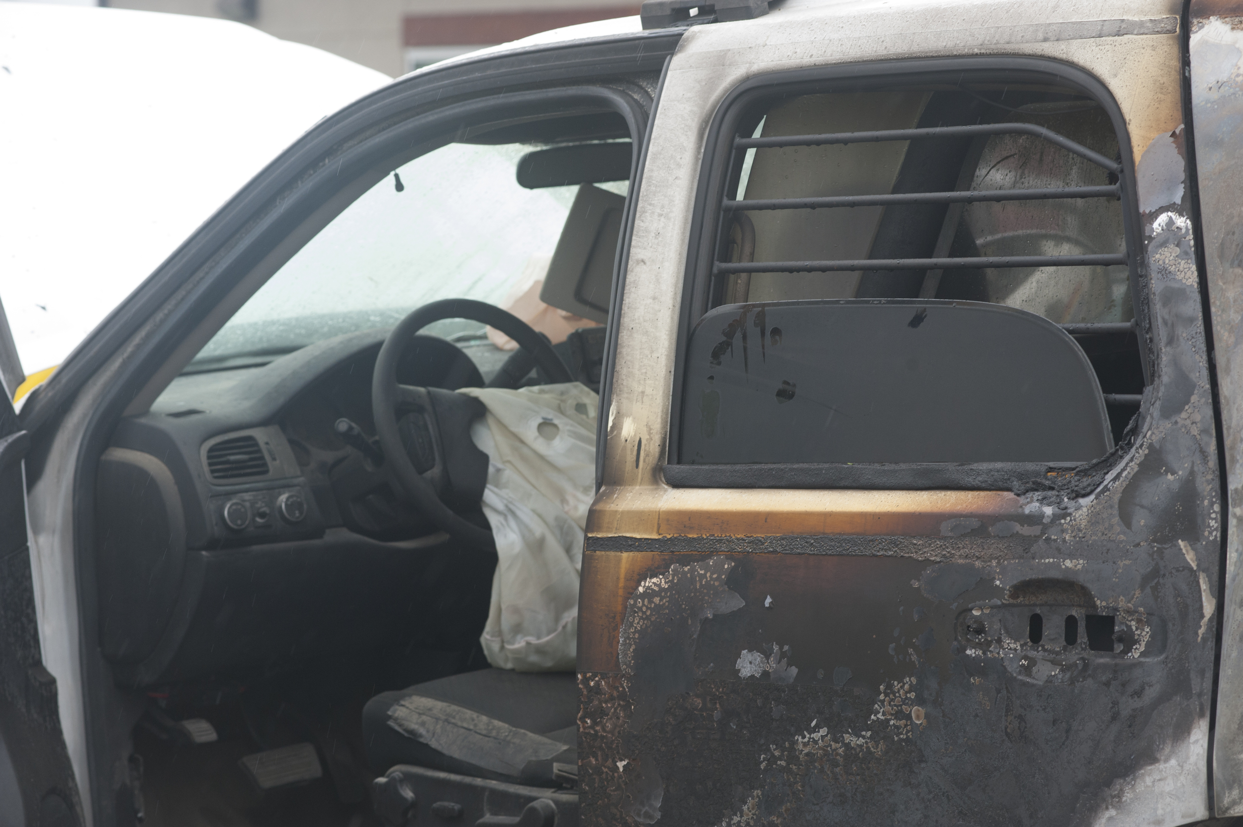 A burned RCMP vehicle, with its airbag hanging from the steering wheel