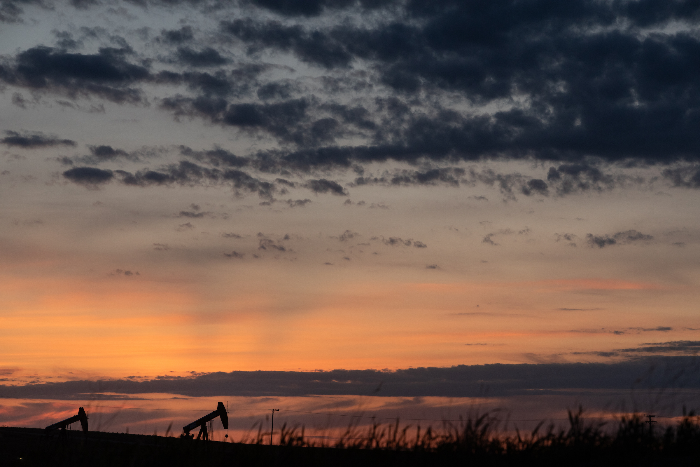 Alberta pumpjacks barely visible over horizon at sunset