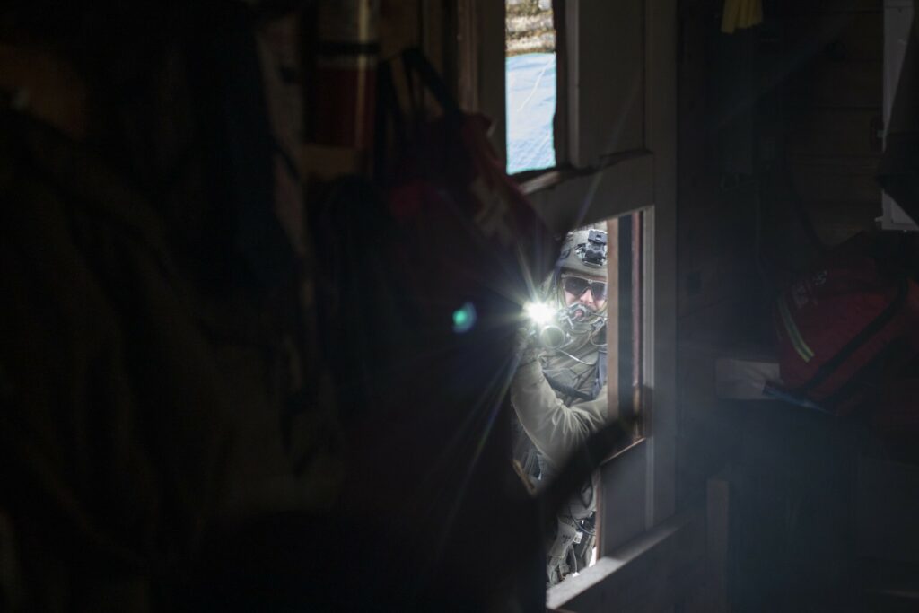 An RCMP officer aims a rifle into a one-room wooden home on Wet’suwet’en territory where land defenders gathered in November 2021 in opposition to construction of the Coastal GasLink pipeline.