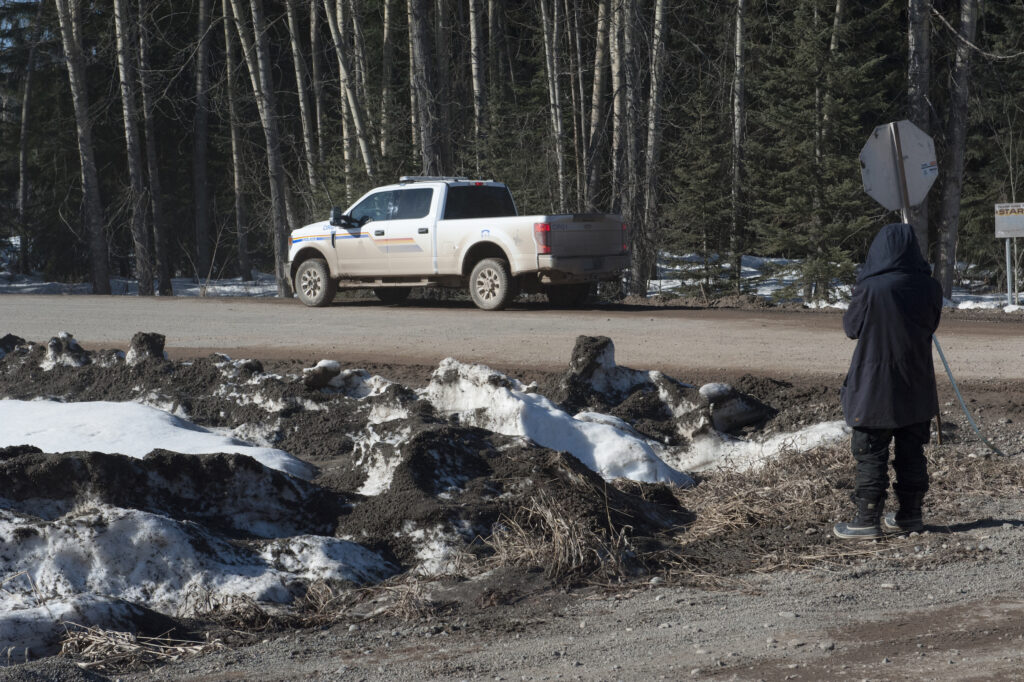 An RCMP truck idles on a backroad on Wet'suwet'en territory with a land defender watching
