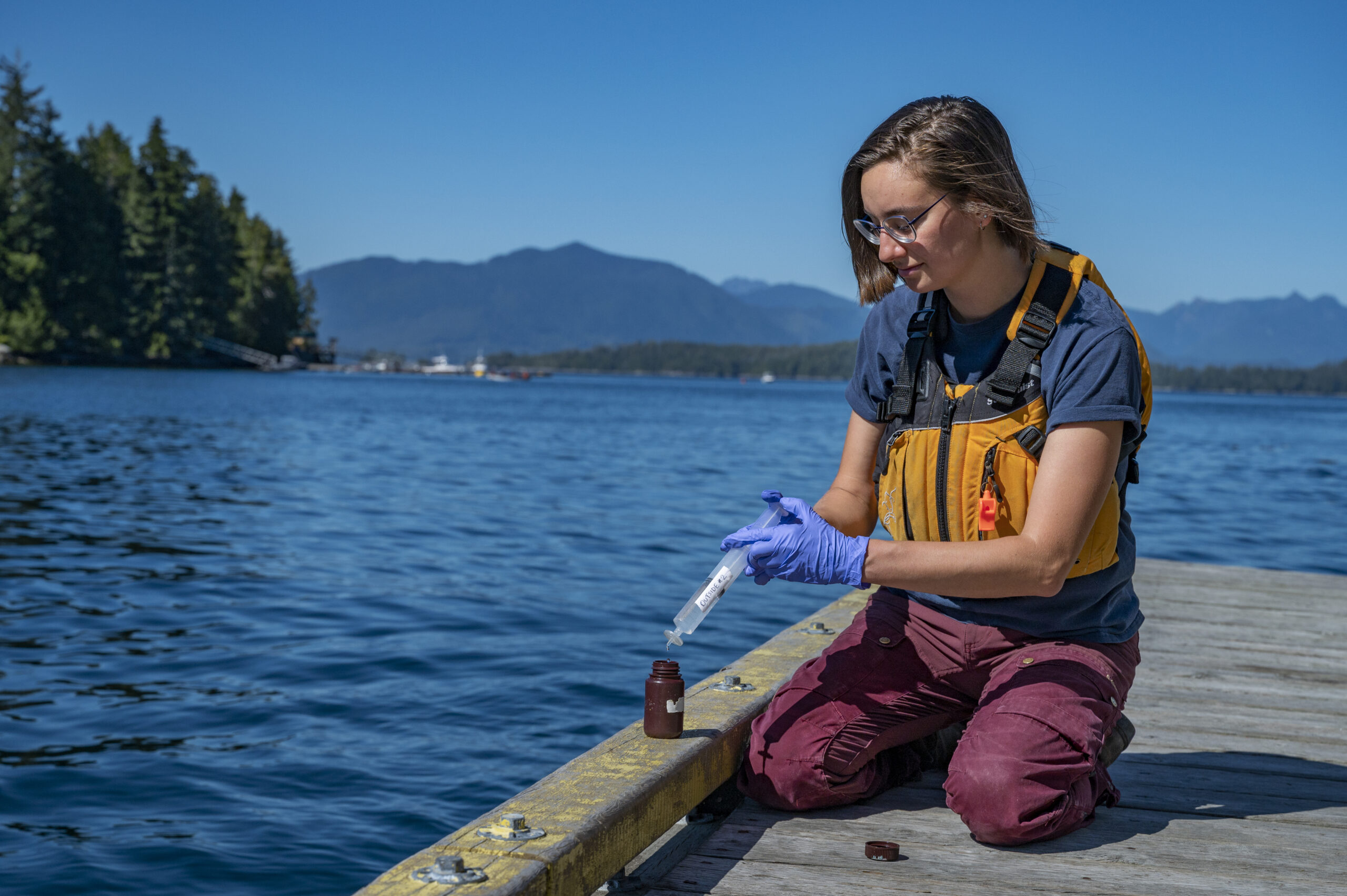 Graduate student Em Lim at the dock in Bamfield demonstrates transfering water samples collected from kelp forests to a sample bottle.