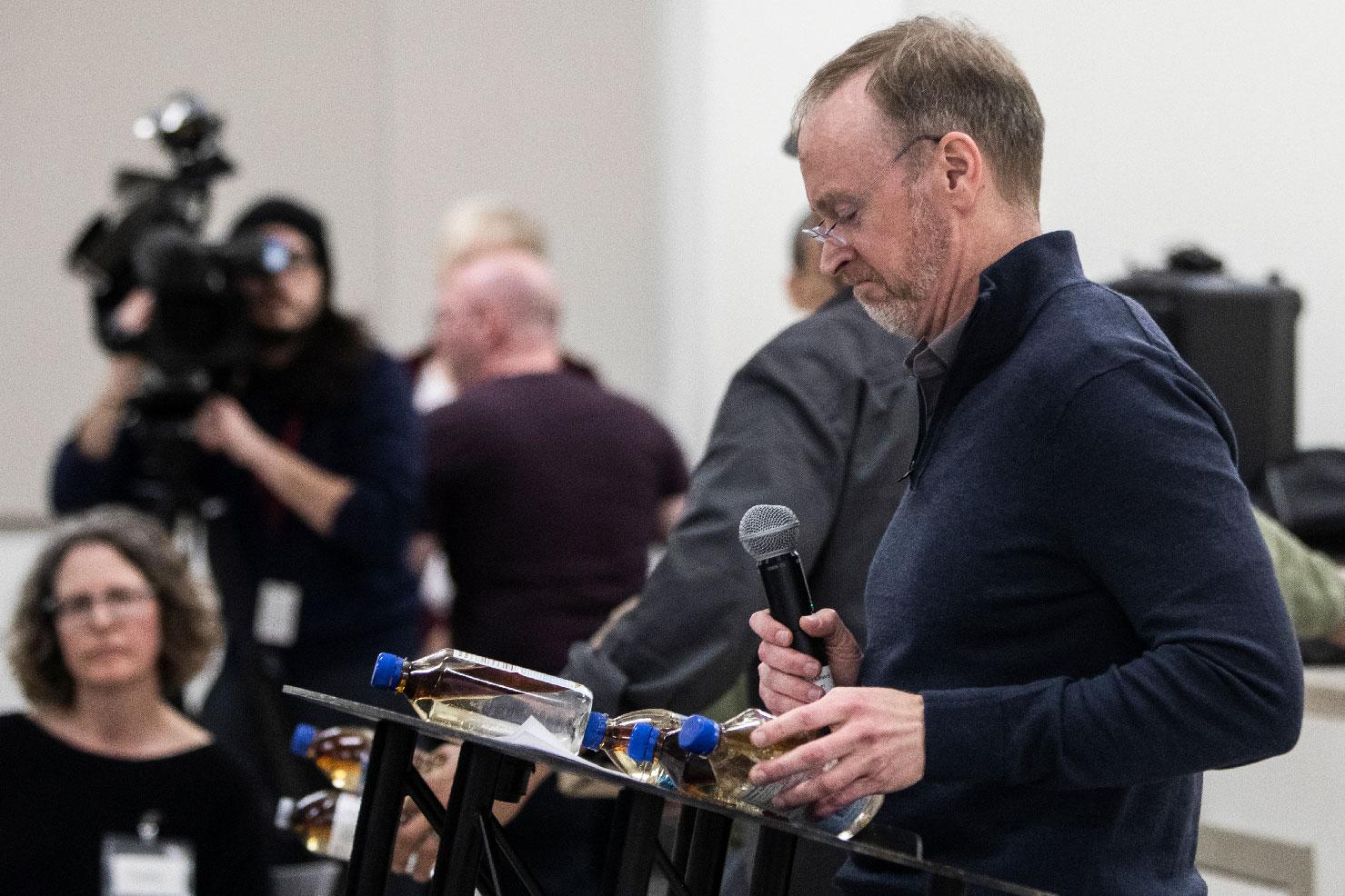 Imperial Oil's vice-president of oilsands mining Jamie Long looks at bottles of oily water placed on his lectern during a meeting in Fort Chipewyan to address the Kearl oilsands tailings leak.