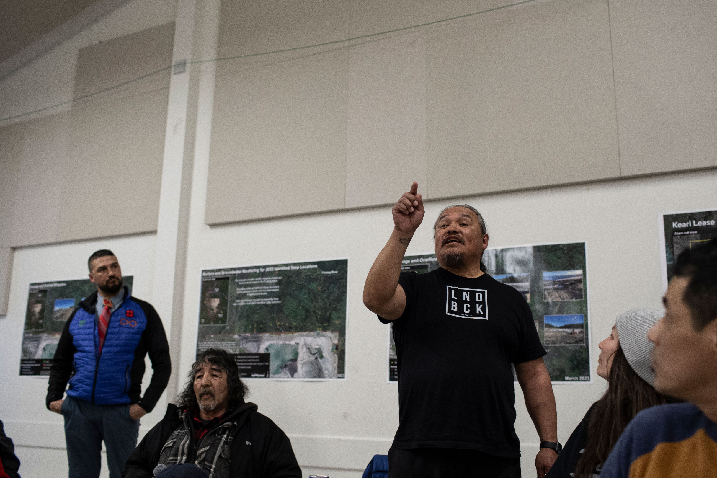 A standing man points at a meeting with Imperial Oil to talk about leaking tailings ponds in Fort Chipewyan, Alta.