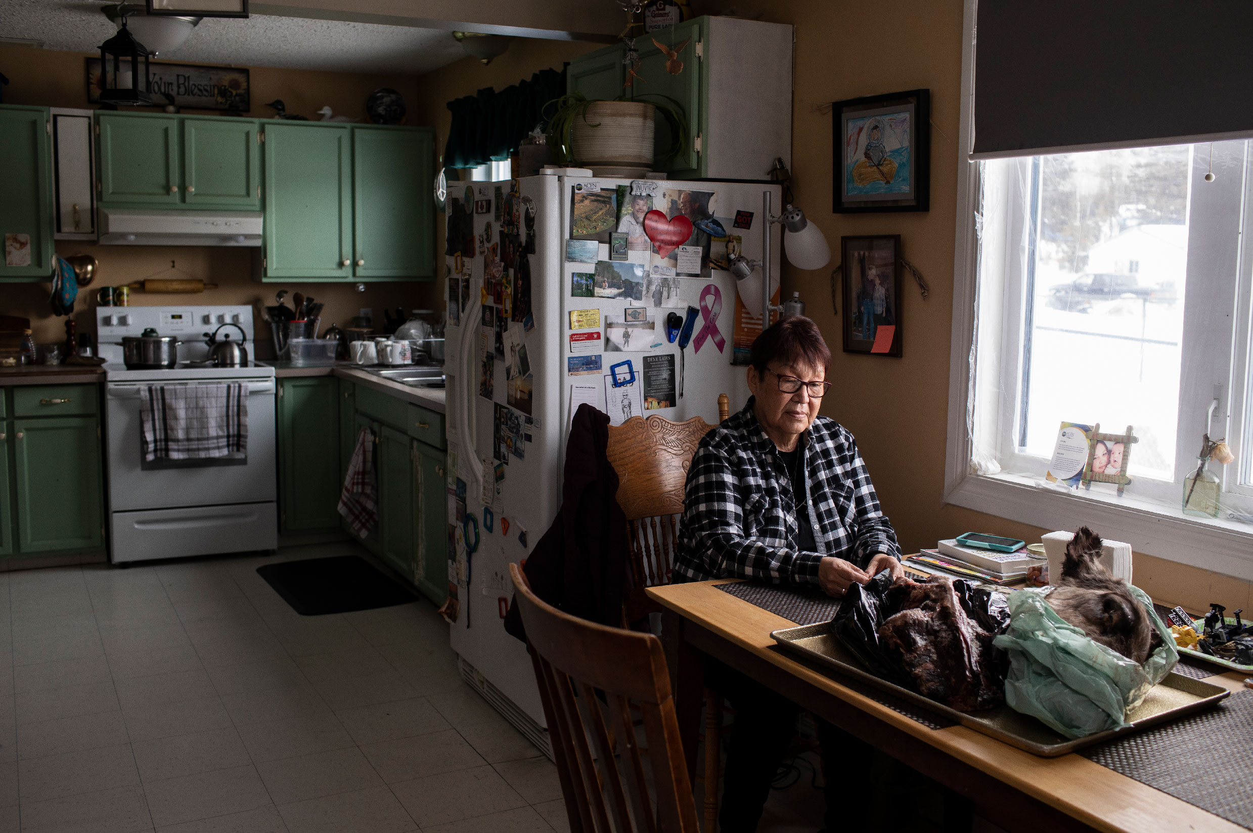 Woman sits in kitchen with moose head on table