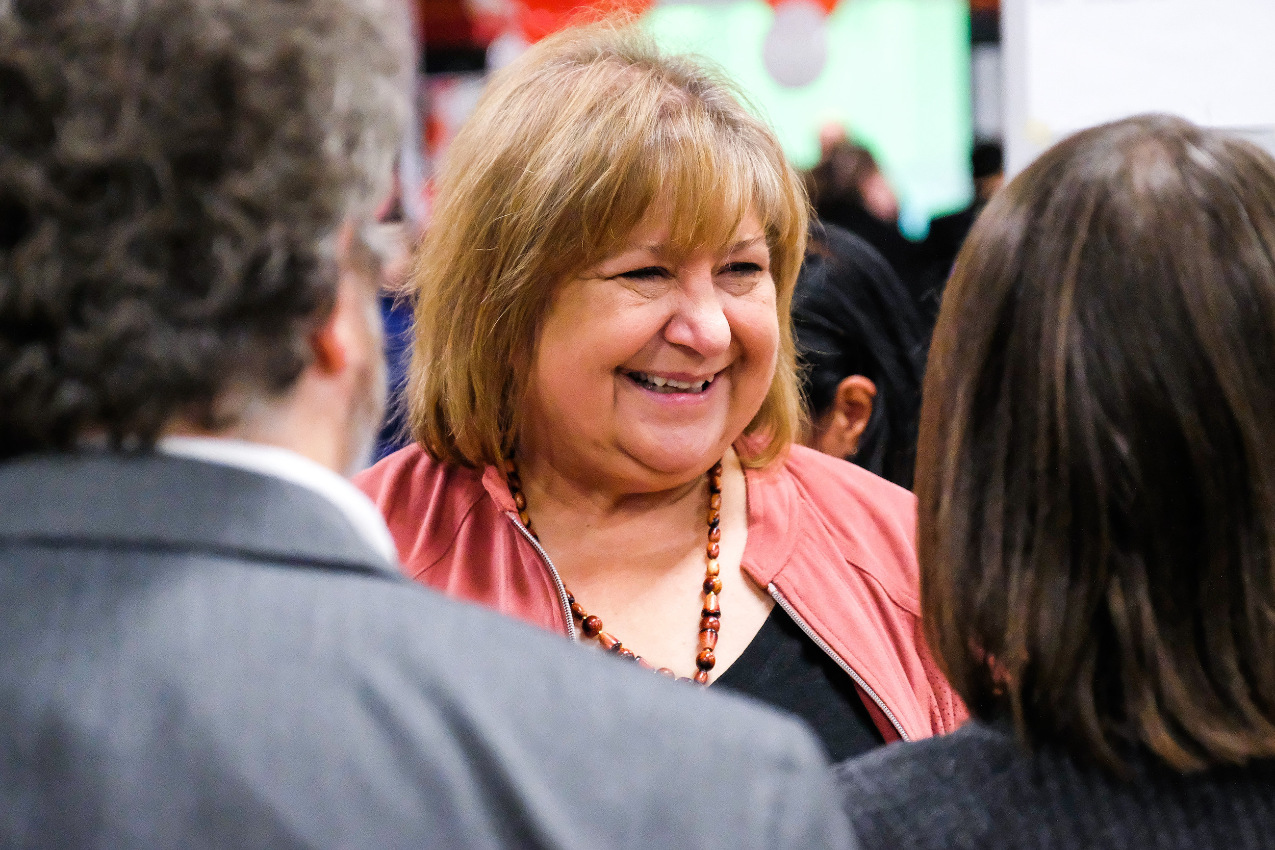 MaryAnn Mihychuk, wearing pink, speaks to two people at an event in 2019
