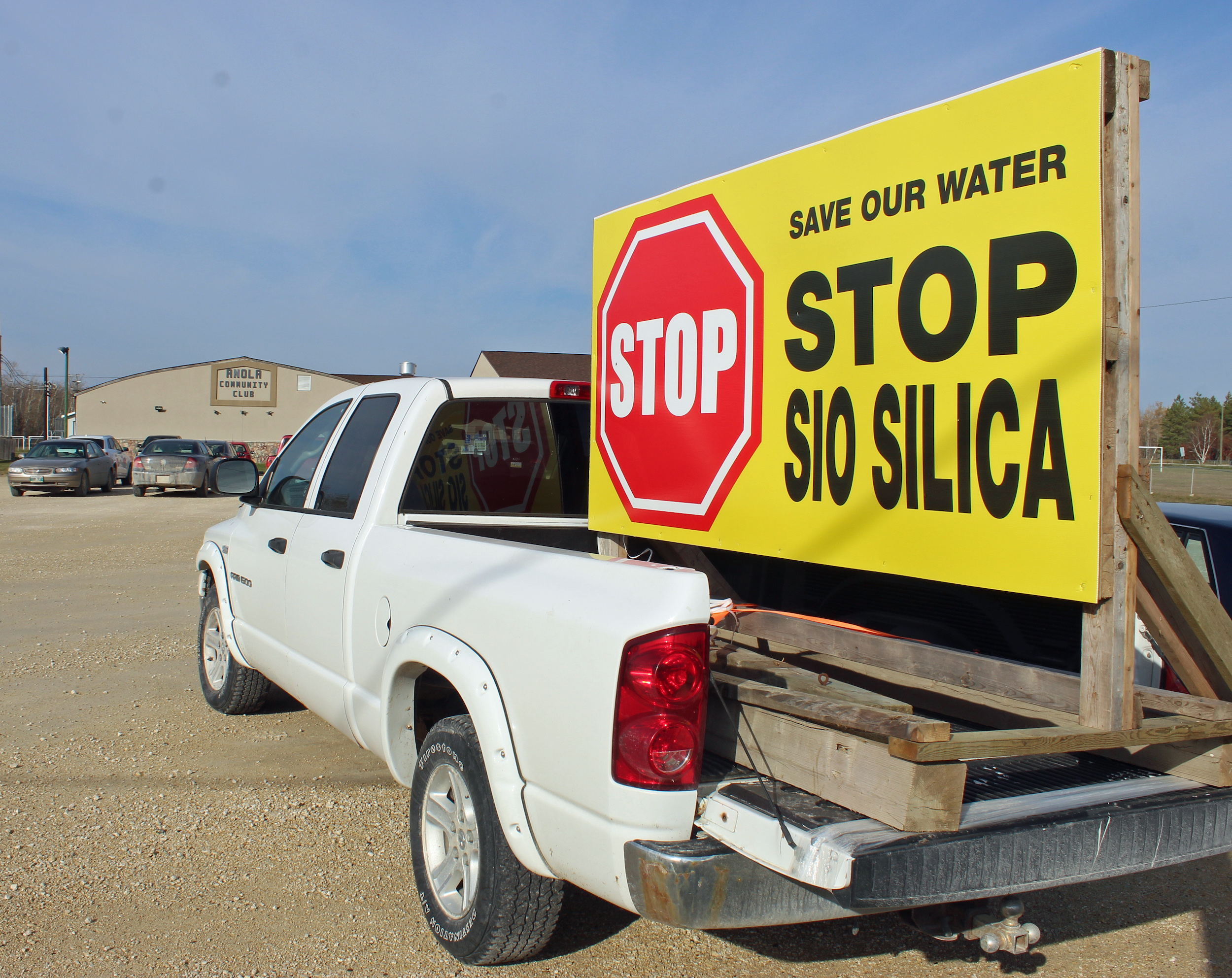 A white pick up truck carries a yellow sign reading "Stop Sio Silica" outside the community club in Anola, Manitoba