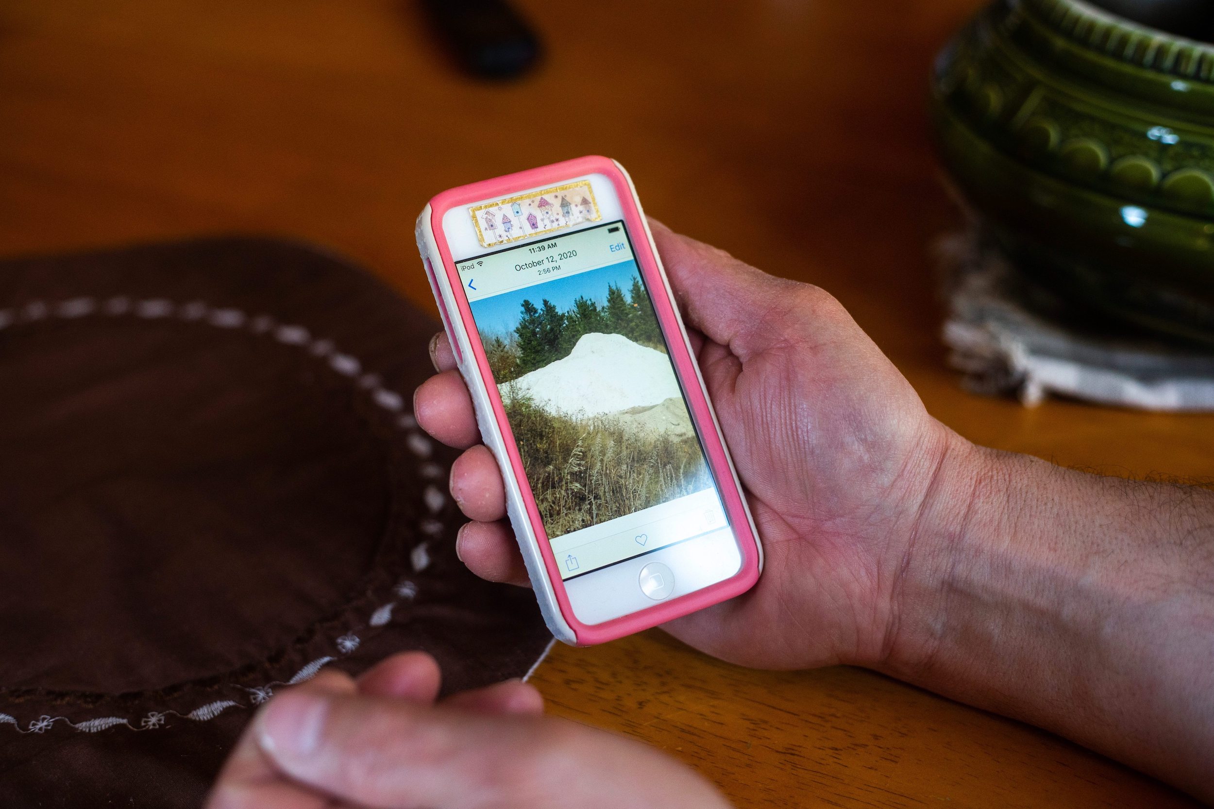 An Anola, Manitoba resident holds an iPhone in a pink case, showcasing a photo of a silica sand pile left uncovered by Sio Silica during exploratory drilling in October 2020