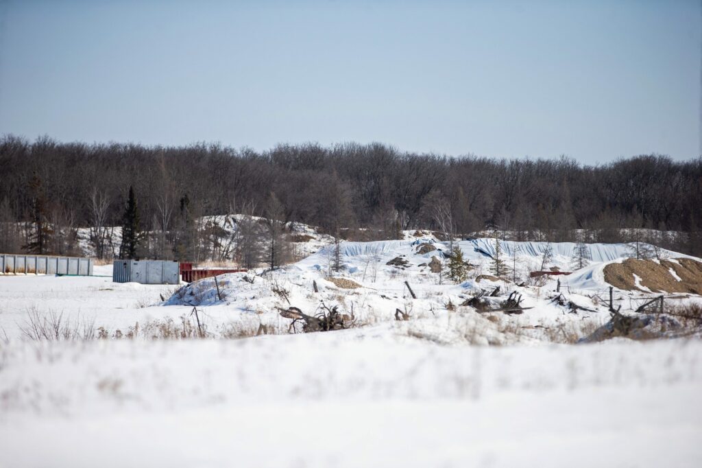 Sand piles covered in white tarps and large metal containers mark the site where Sio Silica has begun exploratory drilling for its proposed silica sand mine near Vivian, Manitoba