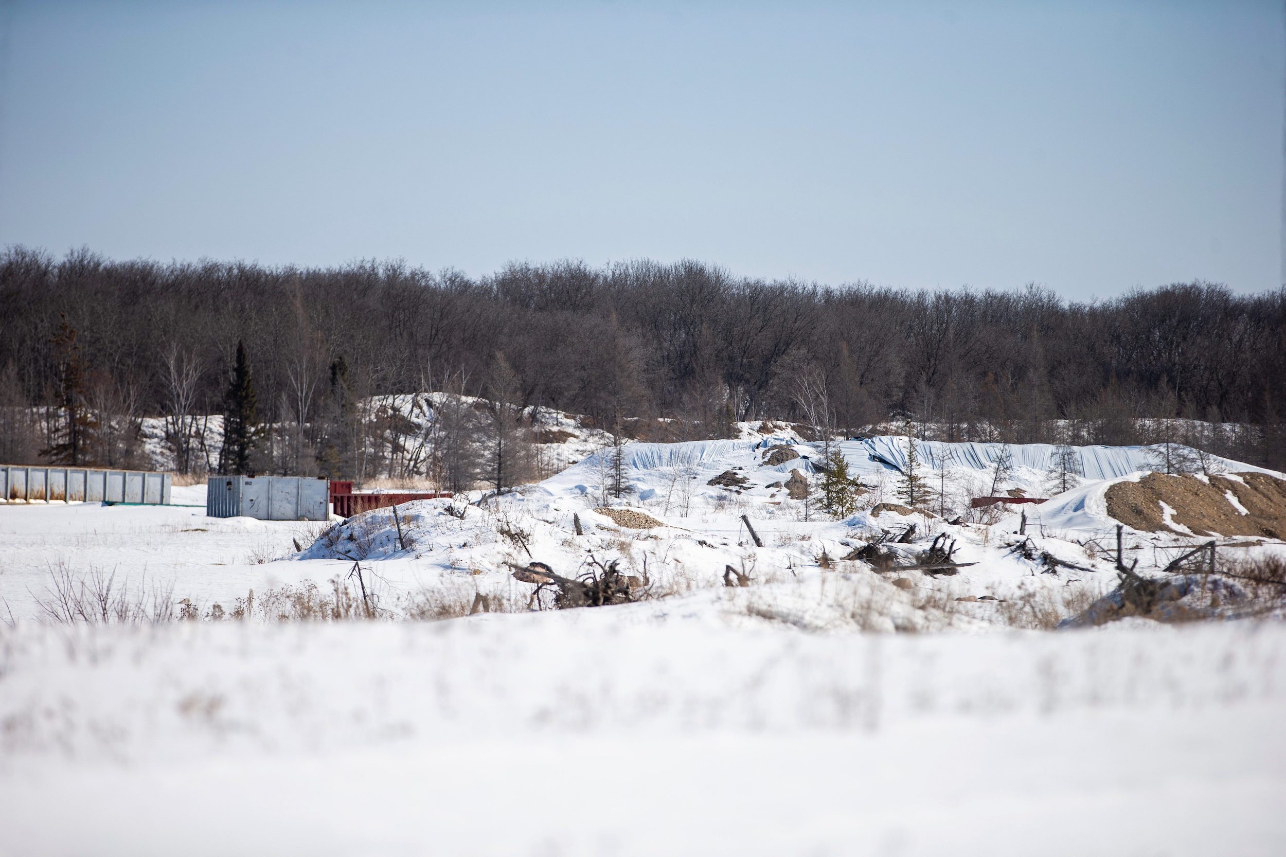 Sand piles covered in white tarps and large metal containers mark the site where Sio Silica has begun exploratory drilling for its proposed silica sand mine near Vivian, Manitoba