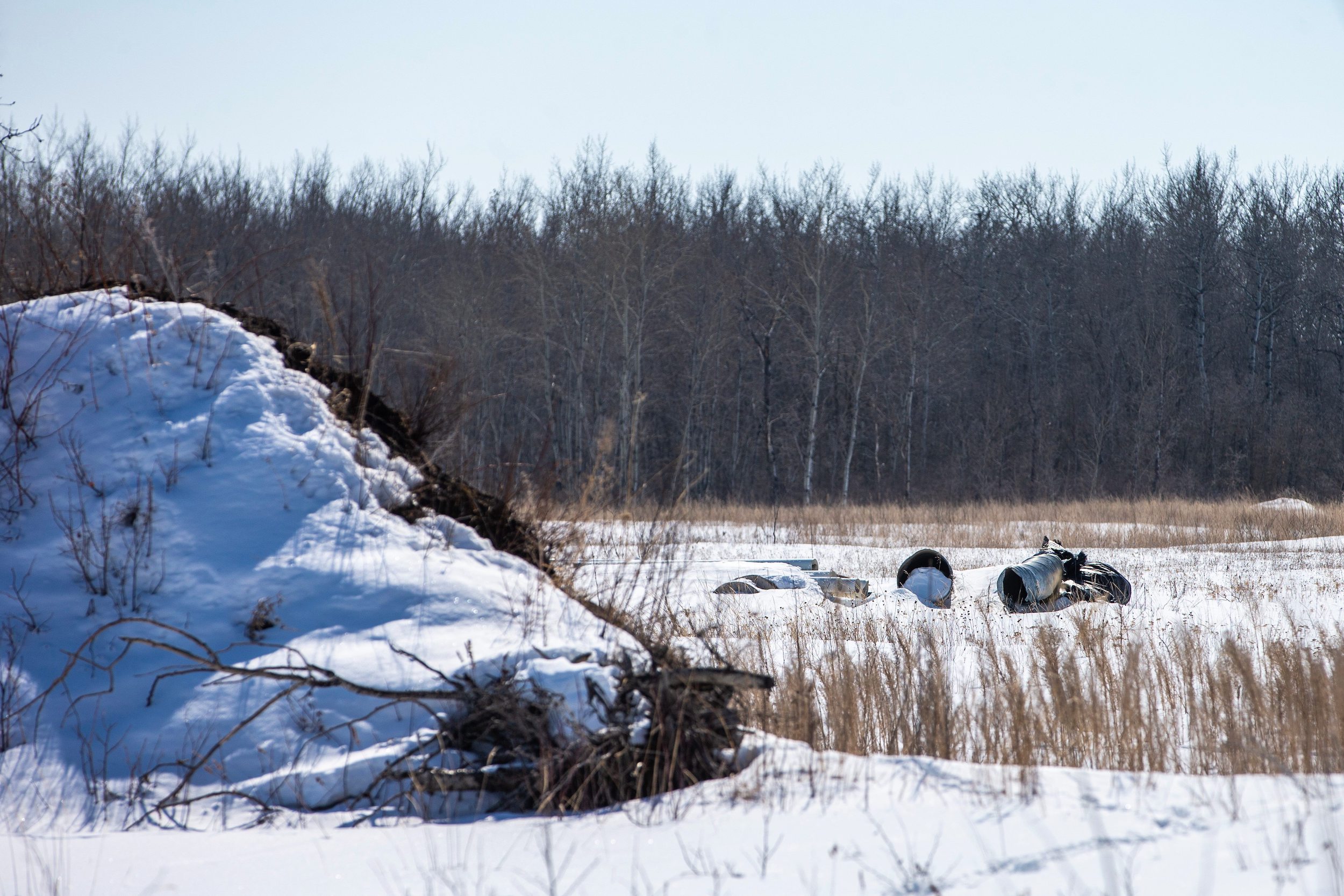 Construction debris lies behind a pile of dirt and snow on the clear-cut land behind the Mustard family's property, where a mining company plans to build a sand processing facility