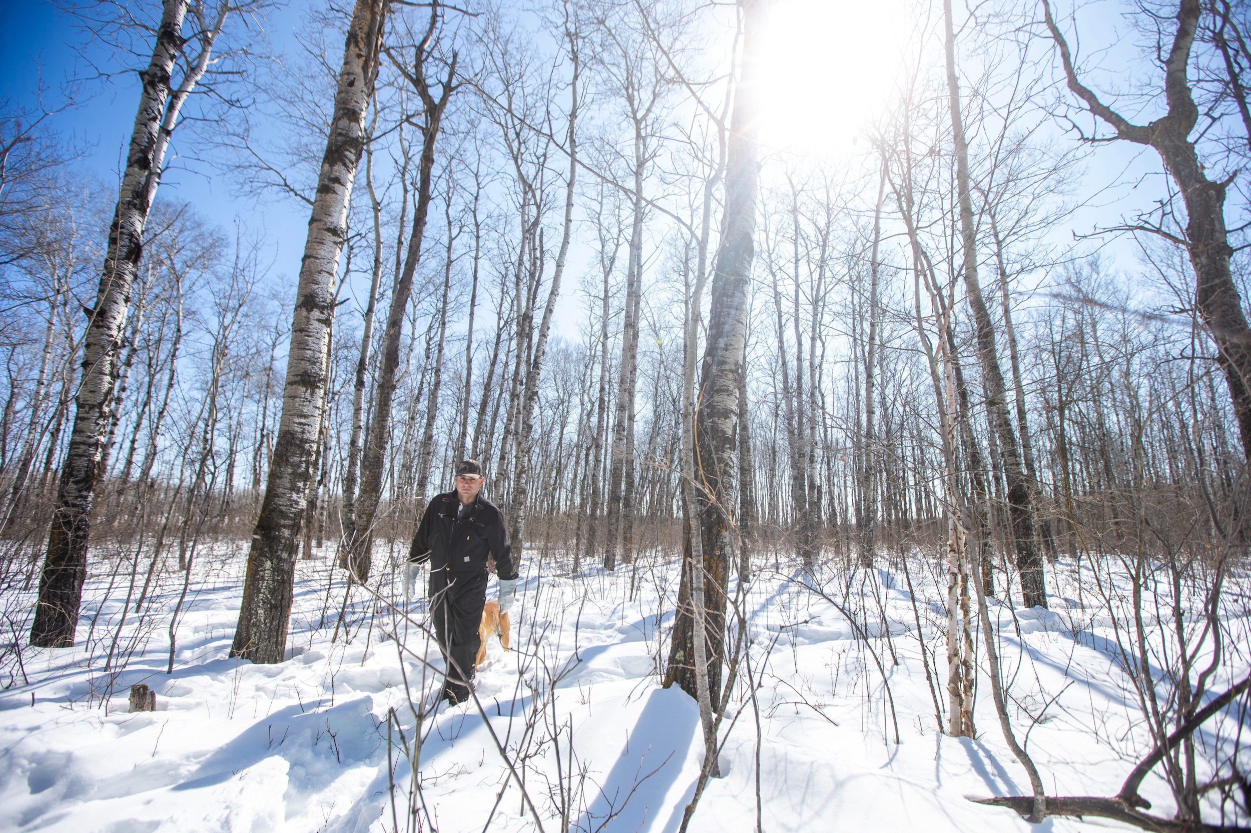 Josh Mustard walks through the snowy forest at the back of his property near Vivian, Manitoba