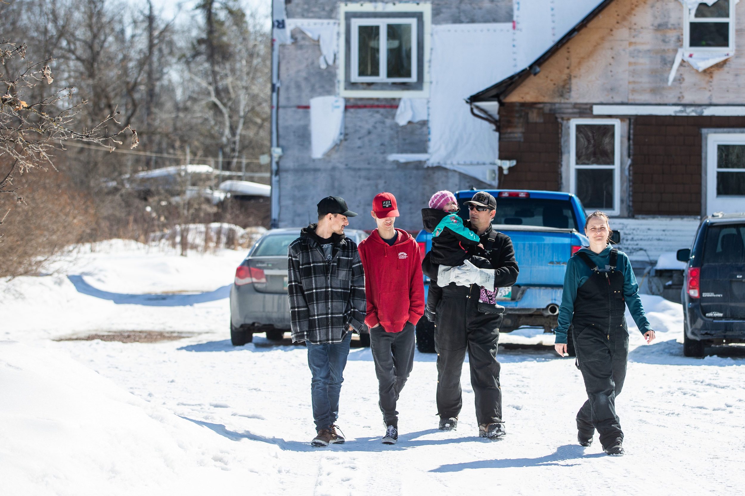Wesley (left), Hunter, Callie, Josh, and Georgina Mustard wear sweaters as they walk through the snow in front of their property near Vivian, Manitoba