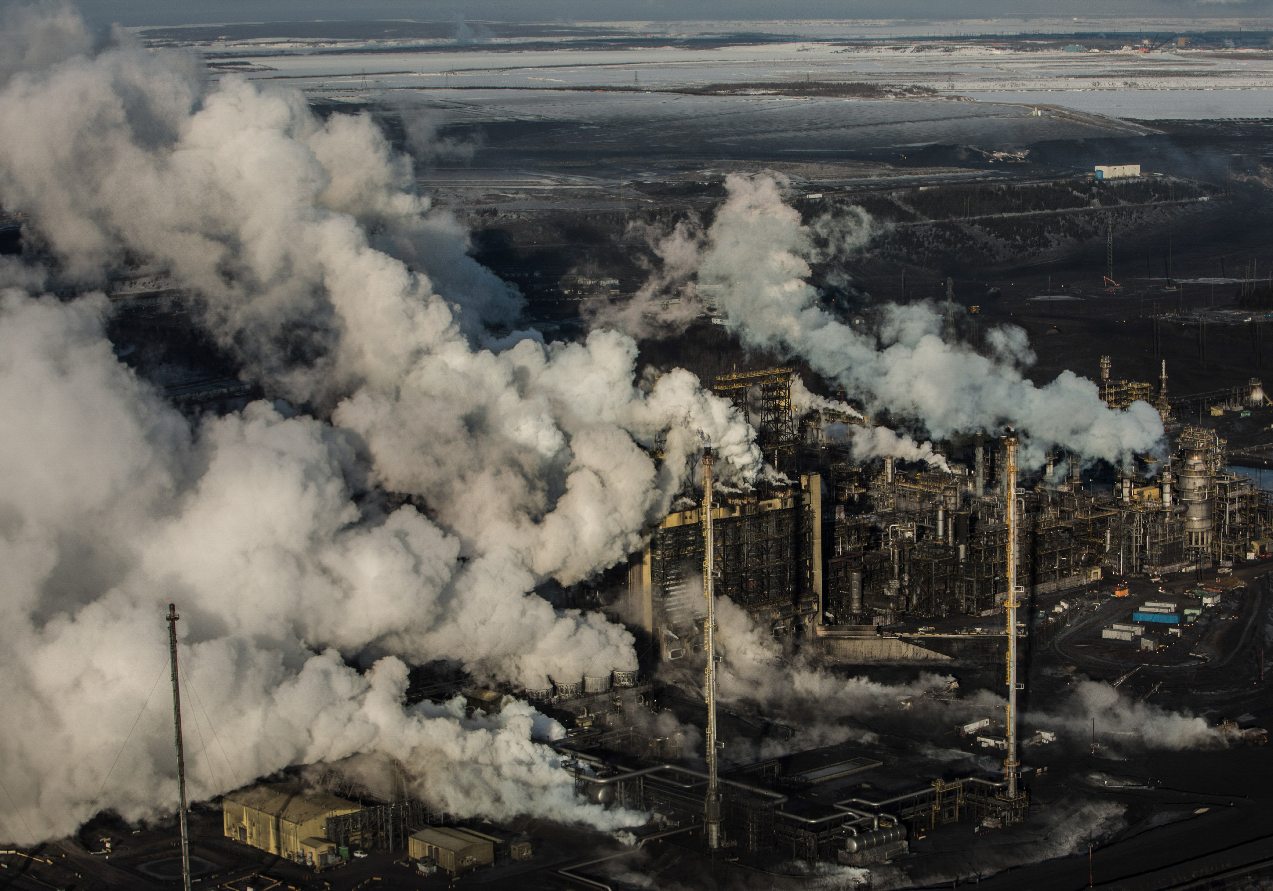 Flyover photo of an industrial facility emitting white smoke or vapour.