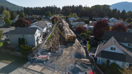Suburban neighbourhood with Trans Mountain construction project through the middle showing pipeline segments.