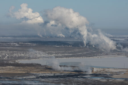 Aerial photo of industrial facilities with large amounts of white smoke or vapour coming out.
