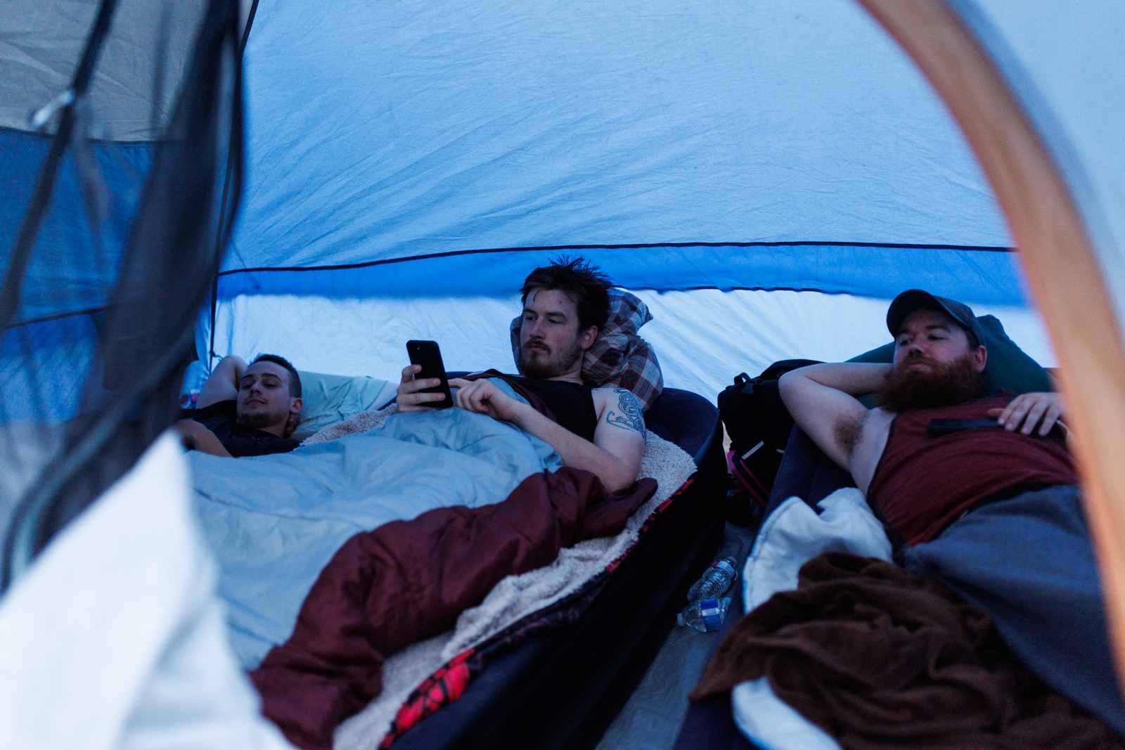 Three medics lie in a shared tent and watch a move after a day on a wildfire in northern B.C.