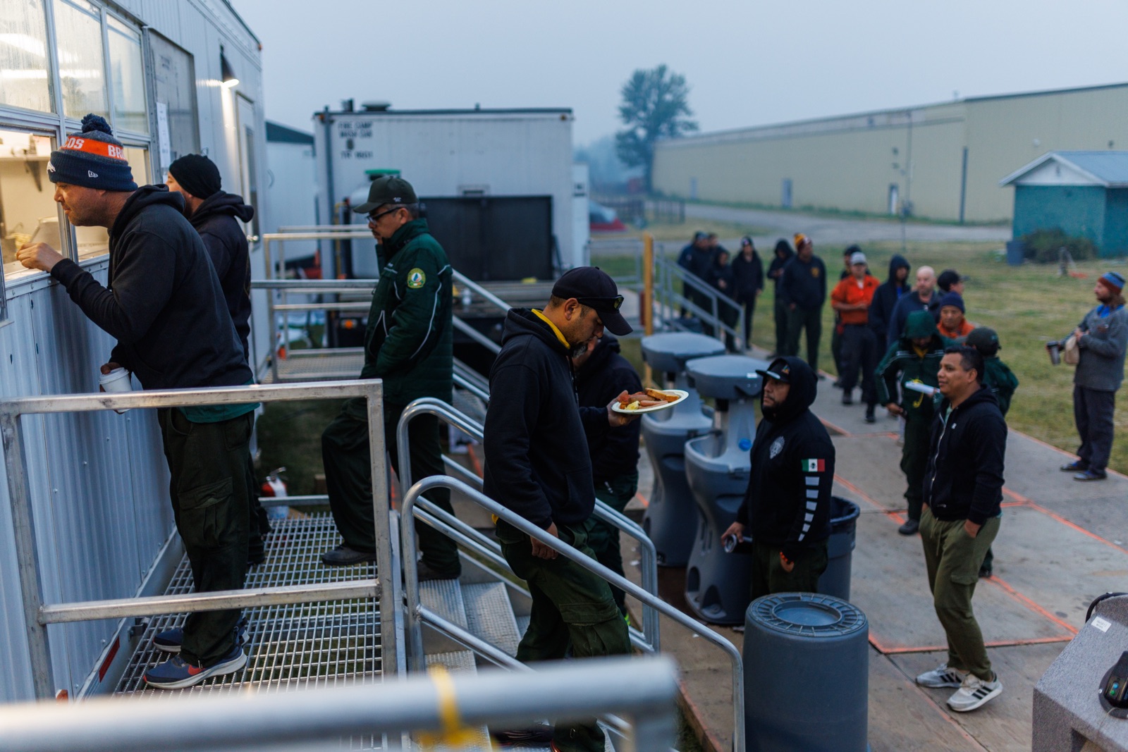 Firefighters line up to collect their breakfast from the catering window at a firecamp in northern B.C.