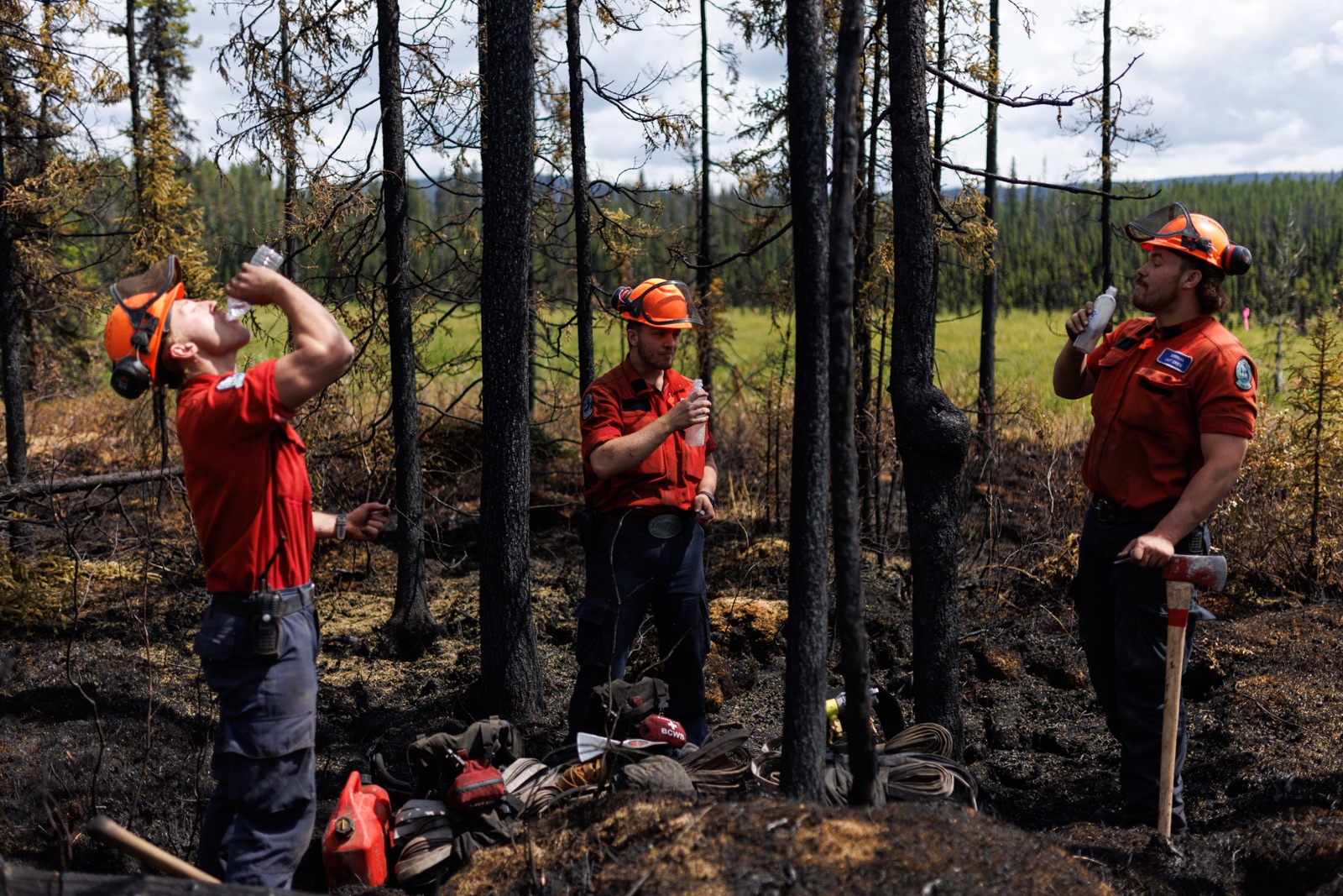 BC Wildfire: Firefights drink water in a burned area of forest