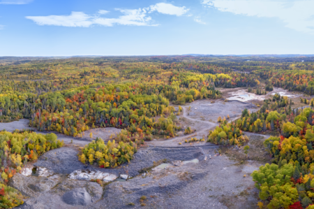 An aerial view of a tailings pond surrounded by forest