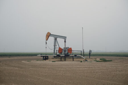 An oil derricks in an Alberta field, with the land cleared around it.