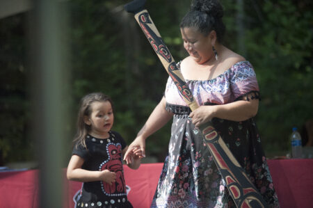 A grandmother and her granddaughter accepting a carved canoe paddle