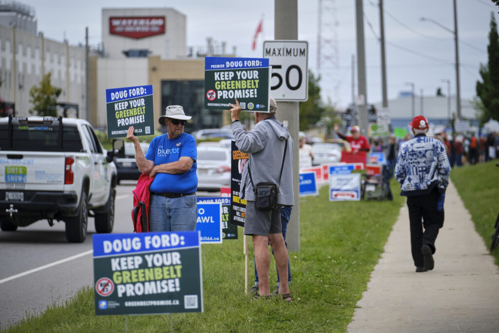 A photo of protestors with signs telling Doug Ford to keep his promise not to open Greenbelt land to development.