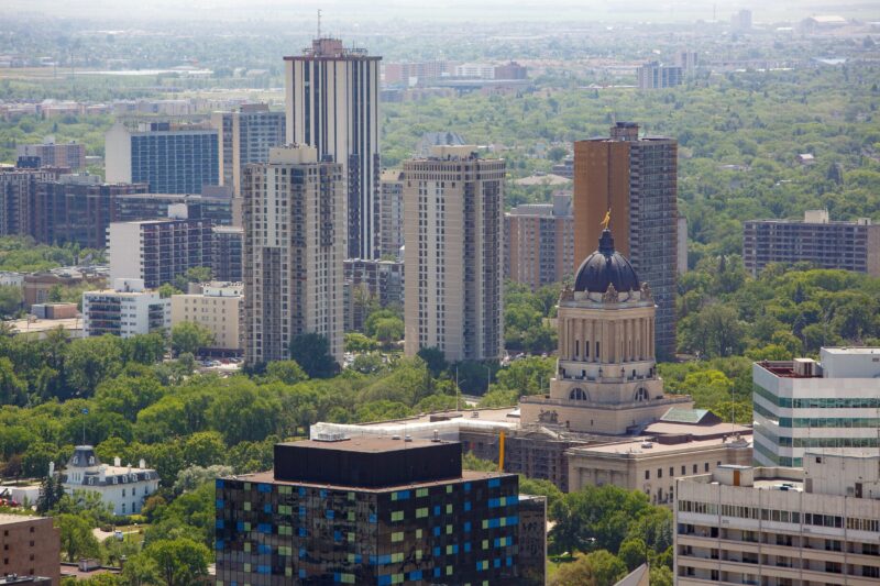 The Manitoba legislature seen from above among tall buildings and treetops