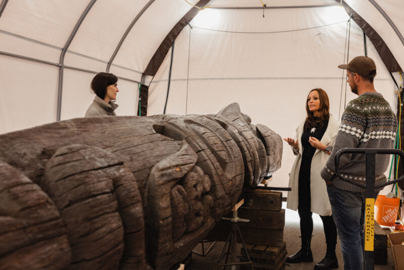 Sigidimnak' Nox̱s Ts’aawit (Amy Parent) speaks to The Narwhal's Matt Simmons and a reporter from the BBC next to the Wilps Ni'isjoohl memorial pole