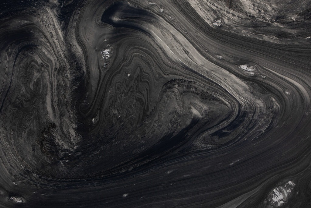 Lines of grey and black sludge at a A tailings pond at a Suncor open pit oilsands mine