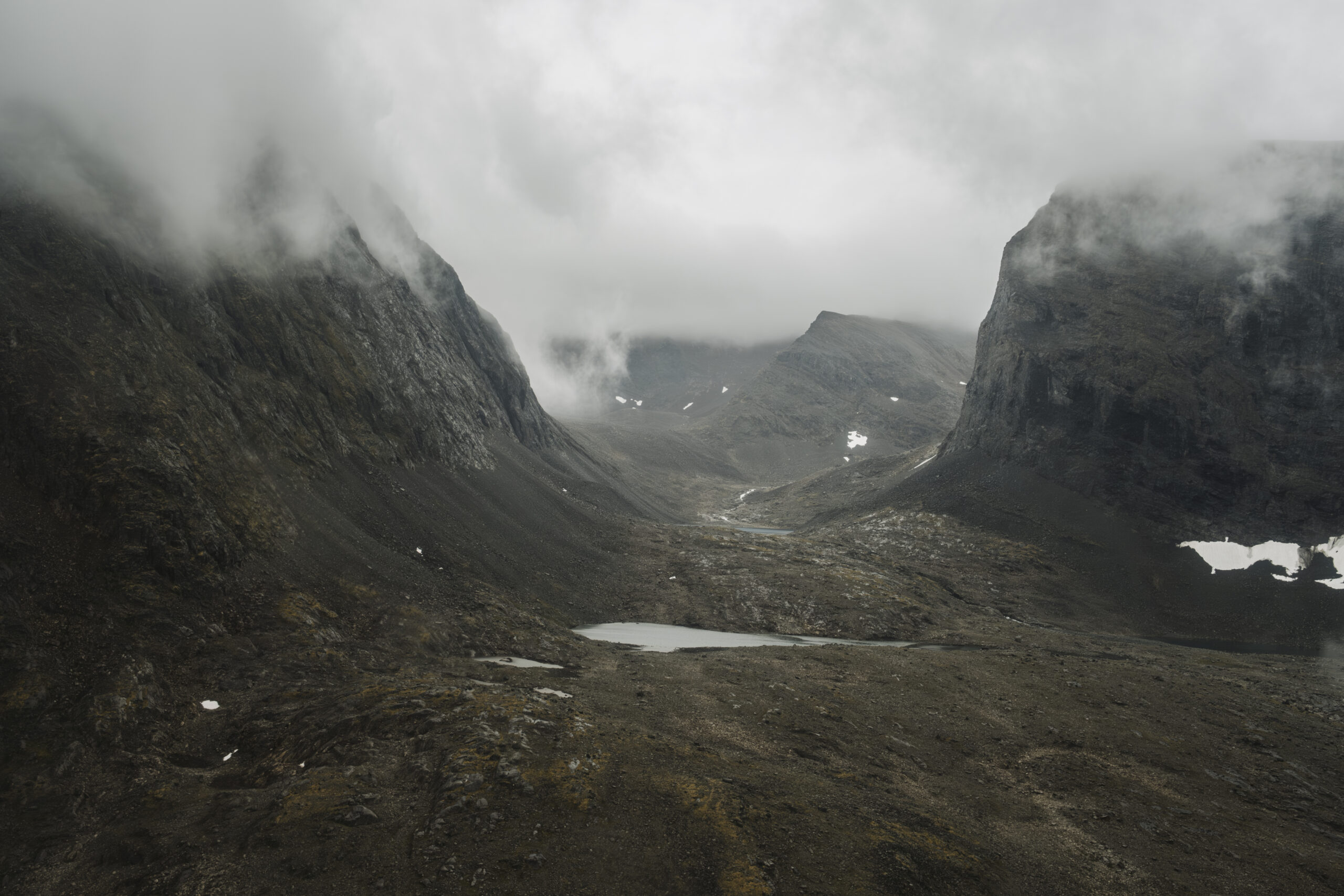 An aerial view of the landscape of Torngat Mountains National Park with clouds descending down into the valley.