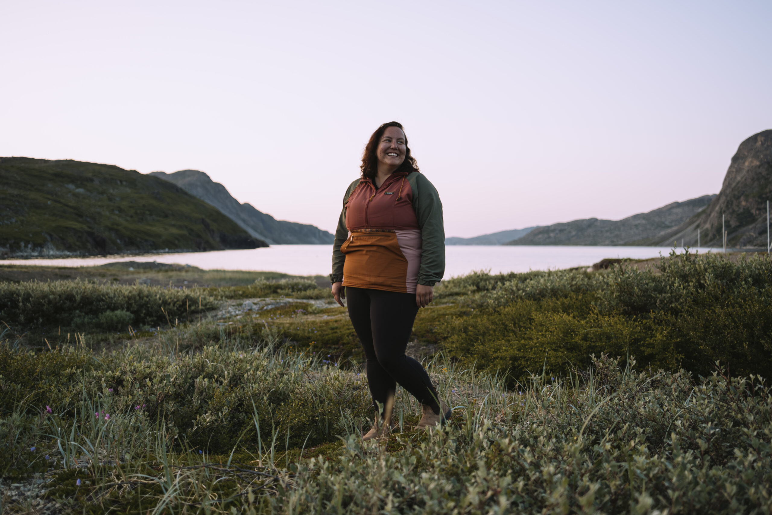 Portrait of Michelle Saunders near shore of St. John's Bay in the Torngat Mountains, with pink sky behind her
