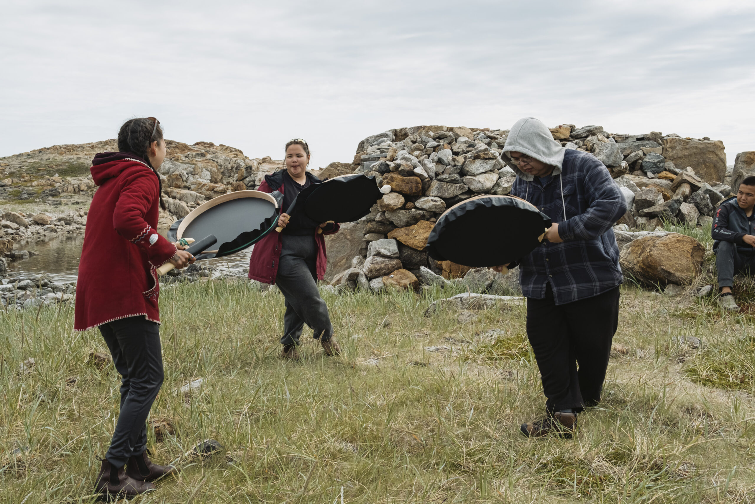 Torngat Mountains National Park: Inuit drummers drum in a circle in front of a rock cairn on Rose Island in the Torngat Mountains