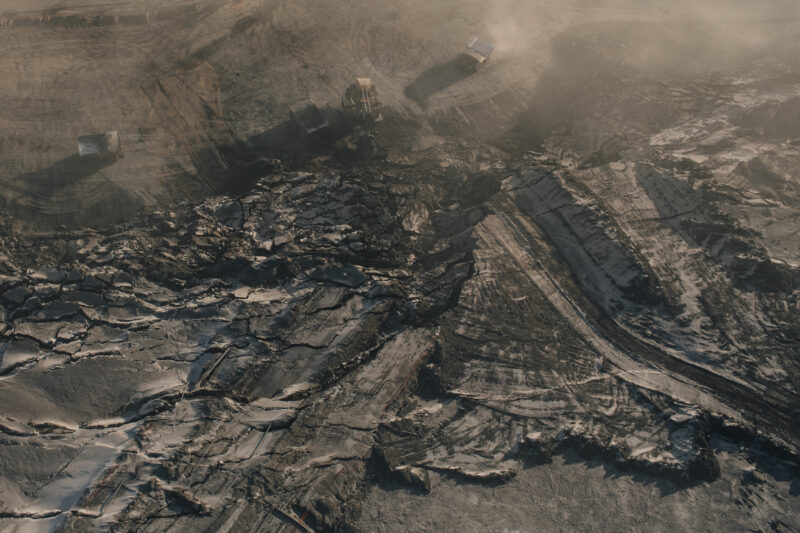 An aerial view of large machinery digging into black earth in the Alberta oilsands