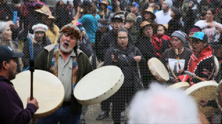 Guujaaw, a Haida Hereditary Chief, drums at totem pole raising on Haida Gwaii