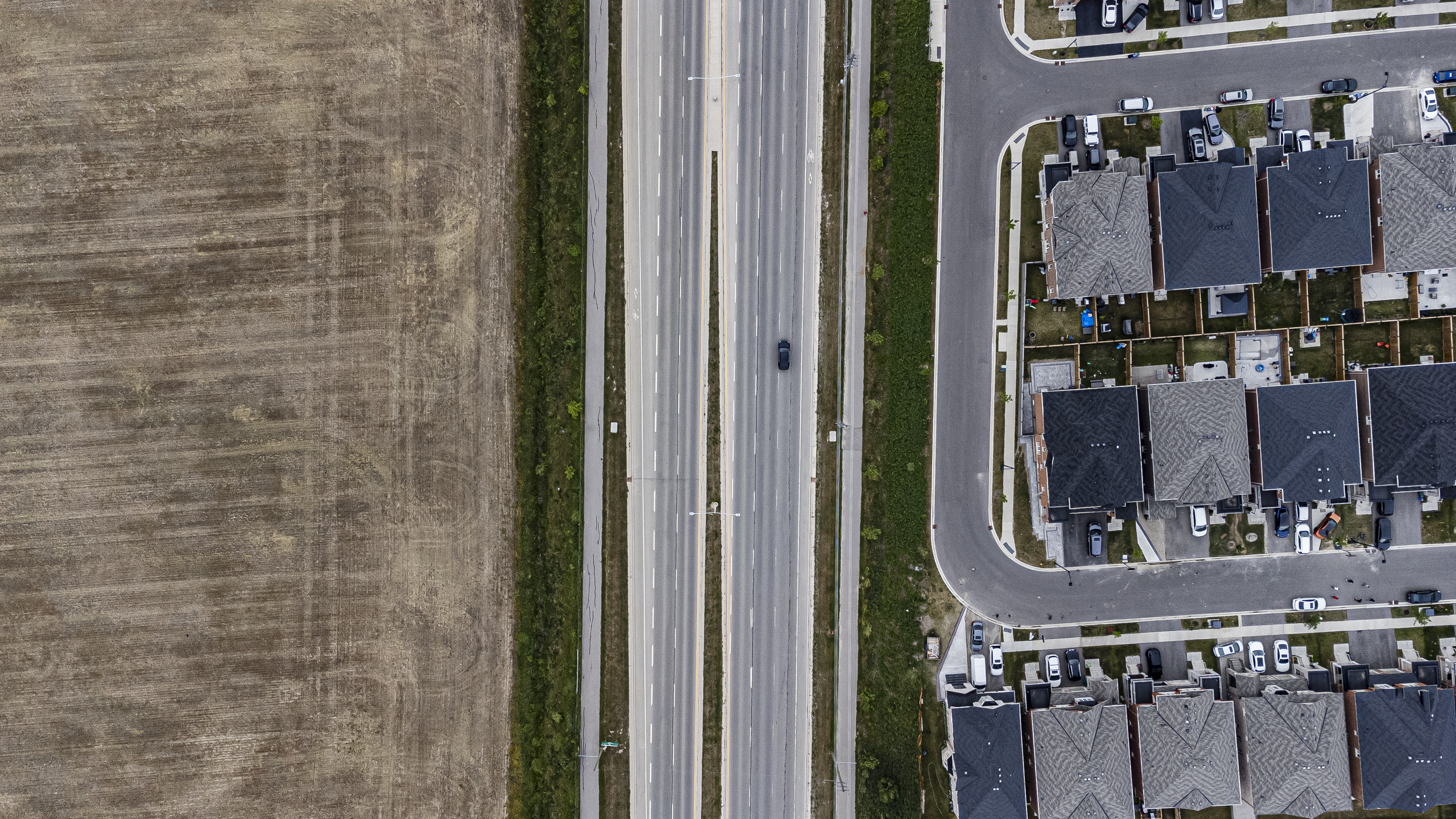 Ontario Greenbelt: a road seen from directly overhead with a neigbourhood on one side and farms on the other